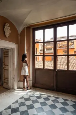 a woman in a white dress looking out of a door at Hotel dei Barbieri in Rome