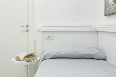 a white bedroom with a bed with a book on a table at Little Aurelius in Rome
