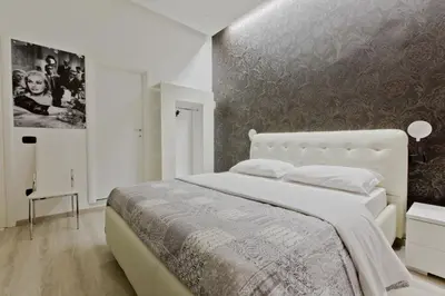 a bedroom with a white bed with a wall at New Rome house 2 in Rome