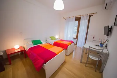two beds in a room with a table and a table at Da Paolo al Vaticano in Rome