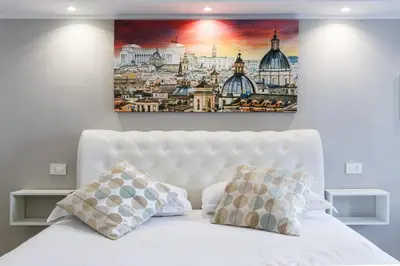 a painting above a white bed with two pillows at Sallustio Fine Rooms Guest House in Rome