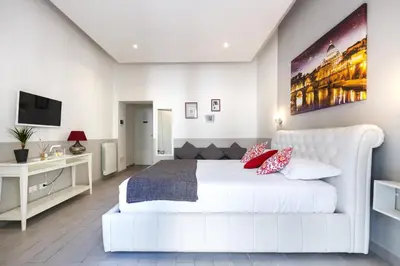 a white bedroom with a white bed and a tv at Sallustio Fine Rooms Guest House in Rome
