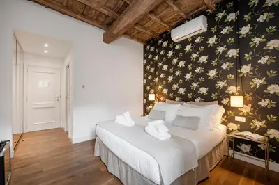 a bedroom with a white bed with a floral wall at i Fiori de' Mario Suites in Rome