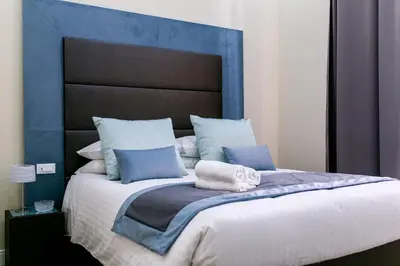 a bed with a blue headboard with towels on it at Bloom Apartment in Rome