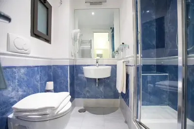 a blue tiled bathroom with a toilet and a sink at Bbqueen in Rome