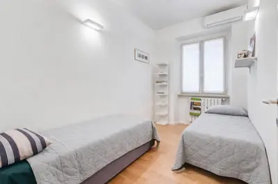 a white bedroom with two beds and a window at Micol's Place, bright apt 2 rooms, 2 toilets, near metro, 80 mq in Rome