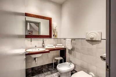 a bathroom with a toilet and a sink and a mirror at Hotel Giuggioli in Rome