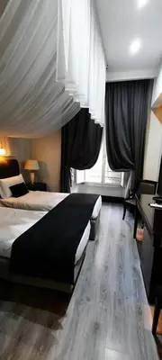 a bedroom with two beds and a large window at Hotel Giuggioli in Rome
