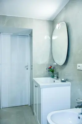 a white bathroom with a sink and a mirror at Appartamento Piazza del parlamento 3 in Rome