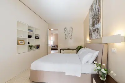 a living room with a white couch and a kitchen at Petra Apartments in Rome