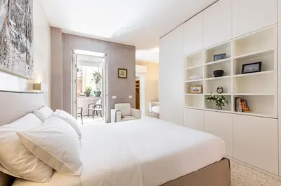 a white bedroom with a large bed and shelves at Petra Apartments in Rome