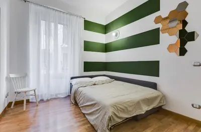 a bedroom with green and white stripes on the wall at San Cosimato House in Rome