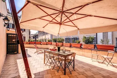 a patio with a table and chairs and a large umbrella at Appartamenti - Via del Monte della Farina in Rome