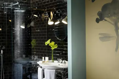 a bathroom with a sink and a black tiled wall at Hotel De' Ricci - Small Luxury Hotels of the World in Rome