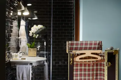 a bathroom with a sink and a toilet and a chair at Hotel De' Ricci - Small Luxury Hotels of the World in Rome