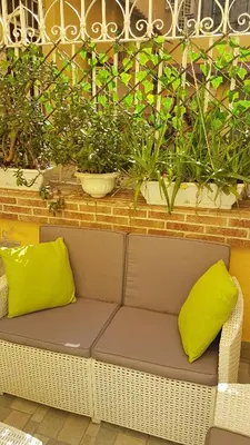 a wicker bench with two lime green pillows at Fabiola's Home in Rome