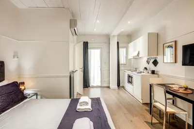 a bedroom with a bed and a table and a kitchen at Colosseo Suite Apartment in Rome