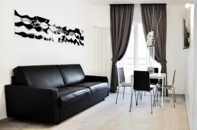 a living room with a black leather couch and a table at LHP Suite Roma Termini in Rome