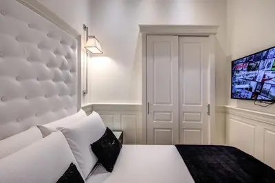 a bedroom with a white bed with a large headboard at Hotel dei Quiriti Suite in Rome