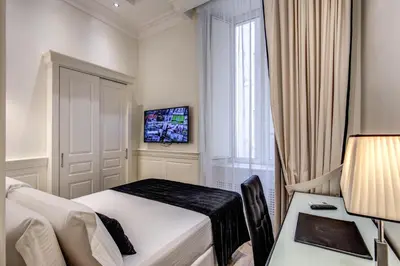 a bedroom with a bed and a desk and a tv at Hotel dei Quiriti Suite in Rome
