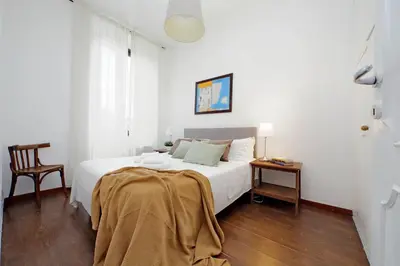 a white bedroom with a bed and a chair at Tevere apartments in Rome
