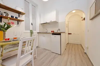 a kitchen with white cabinets and a wooden floor at Tevere apartments in Rome
