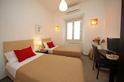 a hotel room with two beds and a desk and a television at Great Central Apartment in Rome