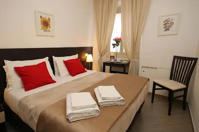 a bedroom with a large bed with red pillows and a chair at Great Central Apartment in Rome