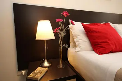 a bed with a red pillow and a lamp on a table at Great Central Apartment in Rome