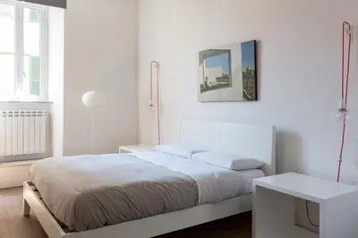 a white bedroom with a bed and a table at Vicoloft Vicolo in Rome