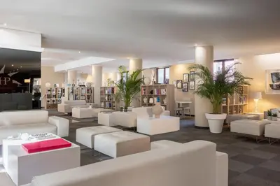 a library with white couches and tables and plants at Phi Hotel Garden Area Roma Eur in Rome