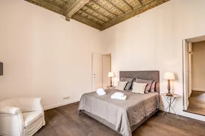 a bedroom with a bed with two lamps and a chair at Piazza Farnese exclusive view 2 bedroom en suite in Rome