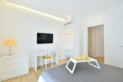 a white room with a bed and a desk and a tv at New Romantic Trastevere Apartment in Rome