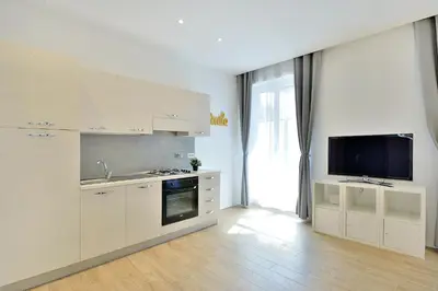 a kitchen with white cabinets and a flat screen tv at New Romantic Trastevere Apartment in Rome