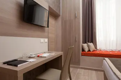 a hotel room with a desk with a tv on the wall at Jackie's Apartments in Rome