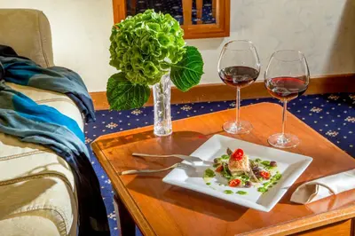 a table with a plate of food and two glasses of wine at UNA Hotels Empire Roma in Rome