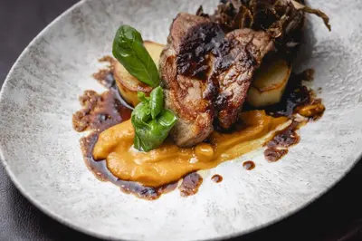 a plate of food with a piece of meat and vegetables at UNA Hotels Empire Roma in Rome
