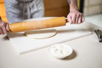 a man holding a rolling pin on a cutting board at UNA Hotels Empire Roma in Rome