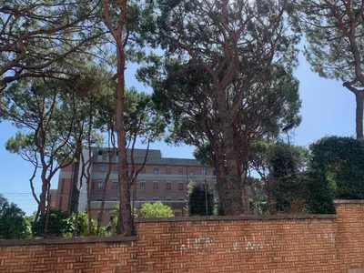 a brick wall with trees in front of a building at Albornoz 35 in Rome