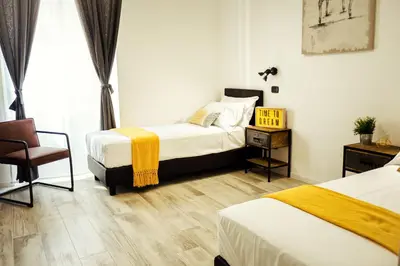 a hotel room with two beds and a chair at BMGA l Stylish Industrial Termini Apartment in Rome