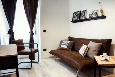 a living room with a brown couch and a table at BMGA l Stylish Industrial Termini Apartment in Rome