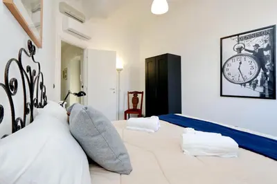 a bedroom with two beds and a clock on the wall at Piazza Capponi Apartment in Rome