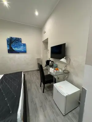 a hotel room with a desk and a bed and a television at RHS Rienzo Suites in Rome
