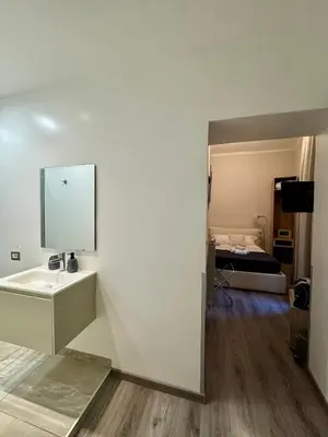 a bathroom with a sink and a mirror and a bed at RHS Rienzo Suites in Rome