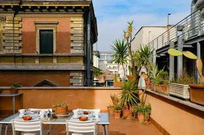 a patio with tables and chairs on a balcony at Spacious Apartment with Big Terrace at Colosseum in Rome