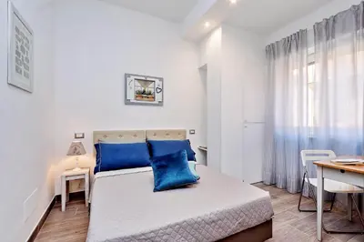 a white bedroom with blue pillows on a bed at La Finestra sul Vaticano in Rome