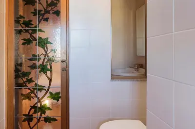 a bathroom with a toilet and a glass shower door at Lago Terrione Apartment - Charme Holidays in Rome