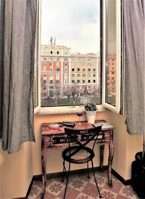 a table and a chair in a room with a window at RomaAmor in Rome
