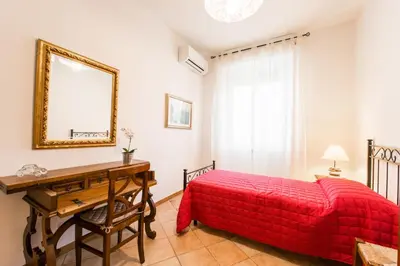 a bedroom with a red bed and a desk and a mirror at Maison Velia San Giovanni in Rome