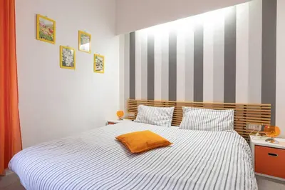 a bedroom with a bed with a orange pillow on it at St Peter Rooms in Rome
